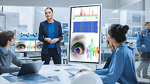 Business professionals in a high-tech meeting room receiving expert training with spectrum monitoring visualizations on screen