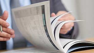 Person browses a printed magazine, representing industry news, insights and SPECTRUM publications