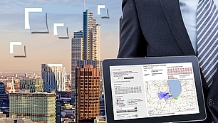 Tablet with spectrum data over a city view representing dynamic spectrum access and RF data analysis.