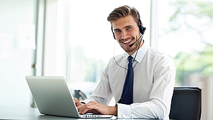 Trainer with headset and laptop representing online seminars and digital training.