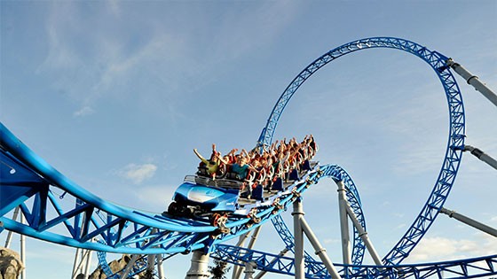 Thrilling ride at Europa-Park. A blue roller coaster with riders enjoying a high-speed loop under a clear sky.